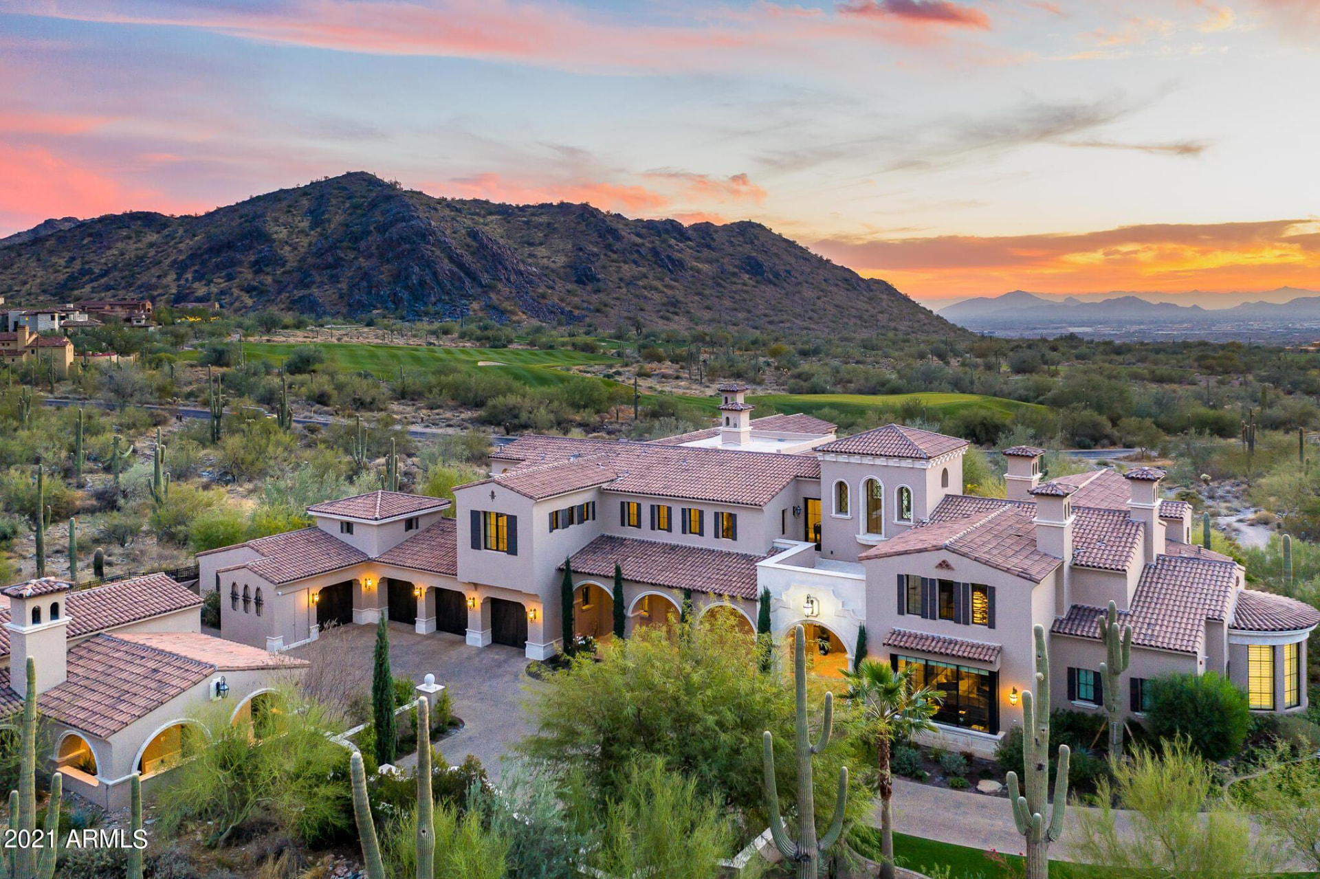 Aerial view of a custom desert estate at sunset with mountain and golf course views