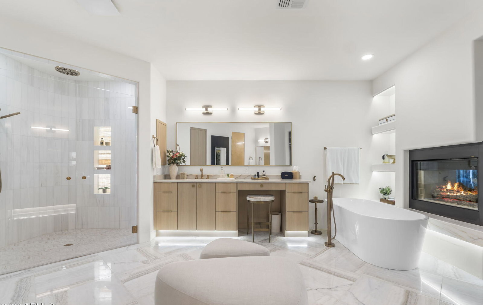 Primary bathroom with freestanding tub, marble floors, and a see-through fireplace